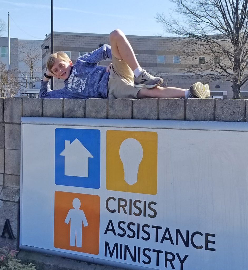 Middle schooler Webb poses at Crisis Assistance Ministry Sign
