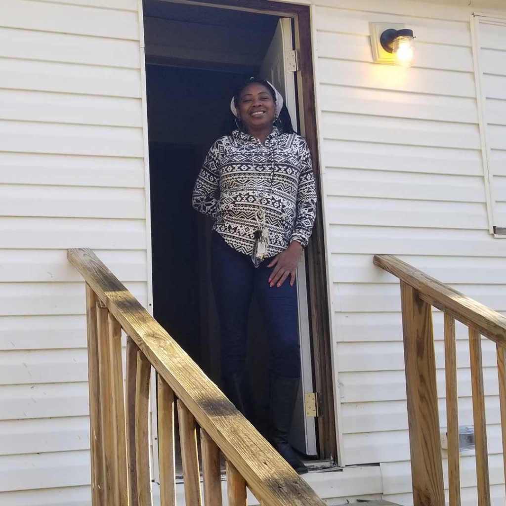 Abigail smiles standing in the doorway of her new home after months of living out of her car or "camping out" with friends.