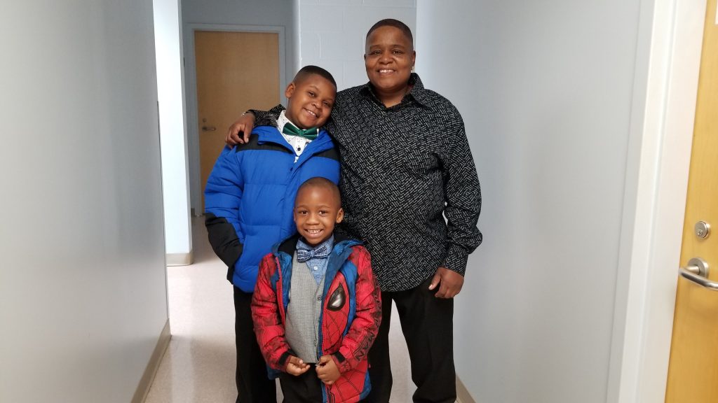 Betty poses with her grandsons who are wearing warm coats they selected free-of-charge from Crisis Assistance Ministry's Free Store.