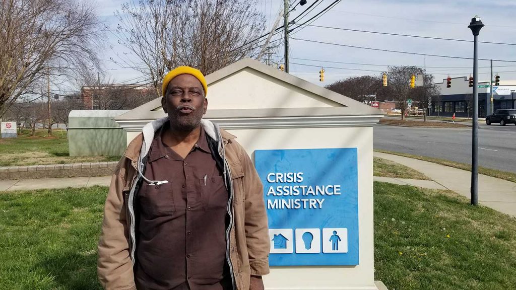 Myron stands in front of Crisis Assistance Ministry sign