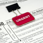 Image of IRS 1040 Individual Tax Form with a binder clip that has a bright red background marker with white words that read "Urgent"